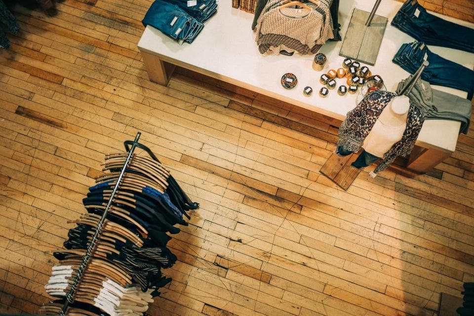Boutique au parquet de bois : table d’accessoires et portant de pantalons