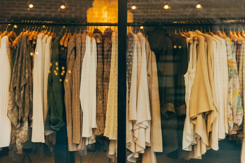 Portant de vêtements aux tons naturels : vestes, chemises et maille en camel, beige et brun